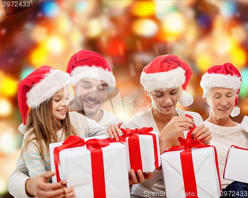 Image of happy family in santa helper hats with gift boxes