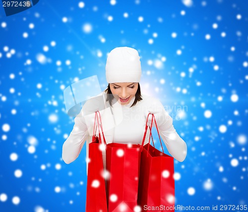Image of smiling young woman with red shopping bags