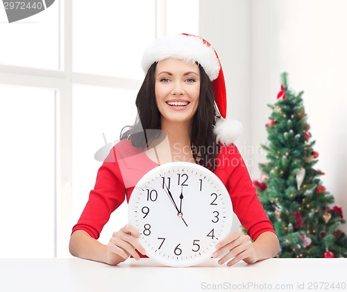 Image of smiling woman in santa helper hat with clock