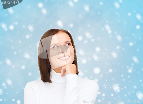 Image of thinking and smiling woman in white sweater