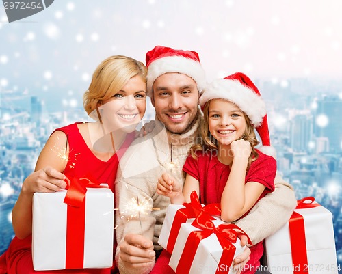 Image of happy family in santa helper hats with gift boxes