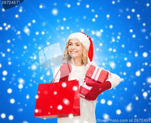 Image of smiling young woman in santa helper hat with gifts
