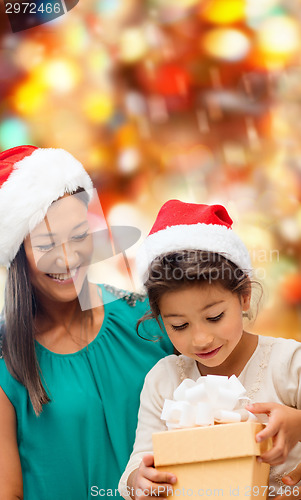 Image of happy mother and girl in santa hats with gift box