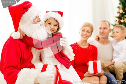 Image of smiling family with santa claus and gifts at home