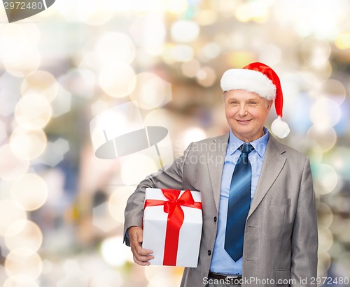 Image of smiling man in suit and santa helper hat with gift