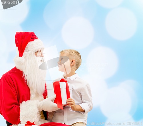Image of smiling little boy with santa claus and gifts