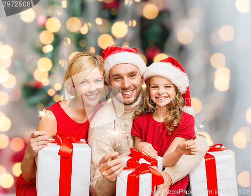 Image of happy family in santa helper hats with gift boxes