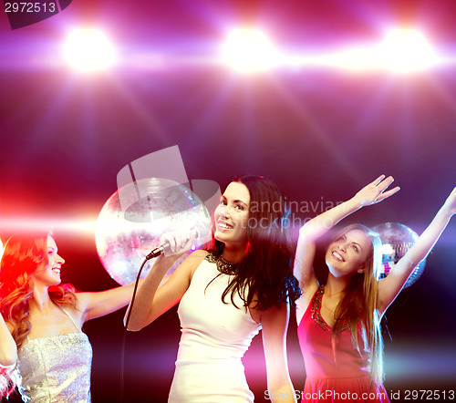 Image of three smiling women dancing and singing karaoke