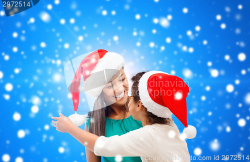 Image of happy mother and girl in santa hats