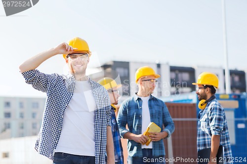 Image of group of smiling builders in hardhats outdoors