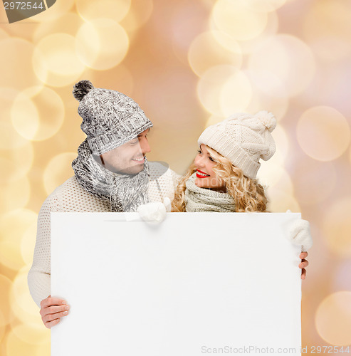 Image of smiling couple in winter clothes with white board