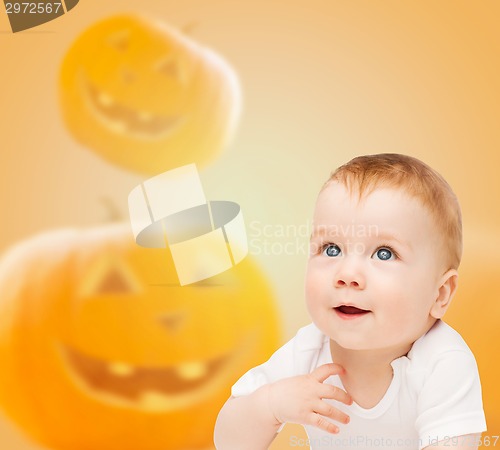 Image of smiling baby over pumpkins background