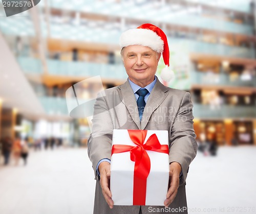 Image of smiling man in suit and santa helper hat with gift