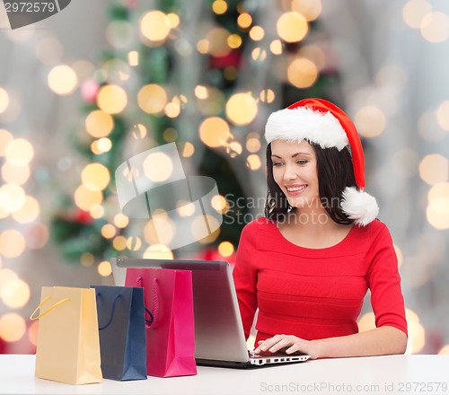 Image of smiling woman in santa hat with bags and laptop