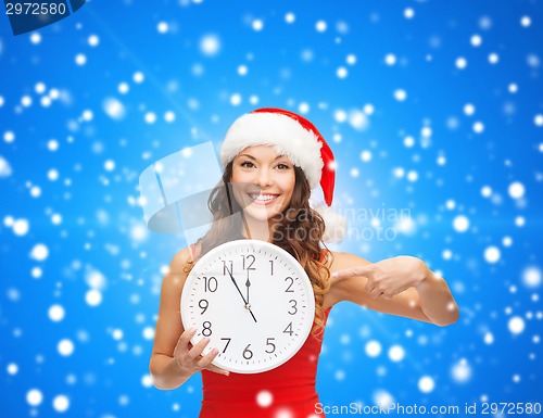 Image of smiling woman in santa helper hat with clock