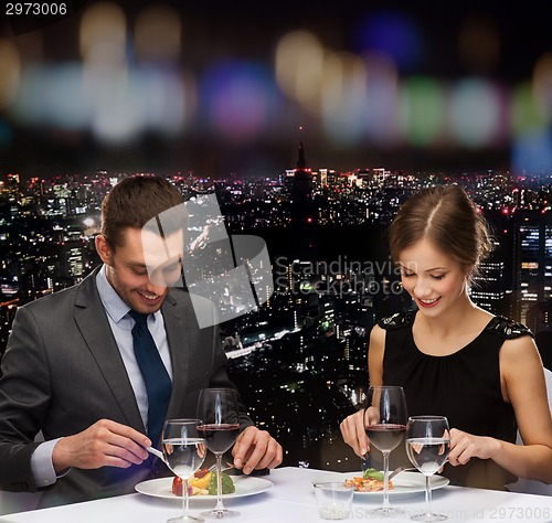 Image of smiling couple eating main course at restaurant