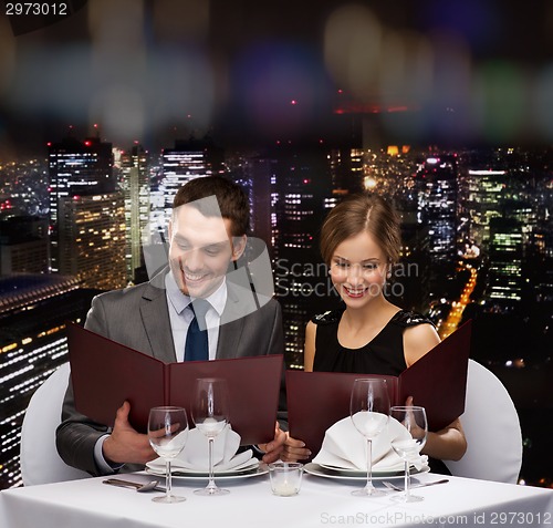 Image of smiling couple with menus at restaurant