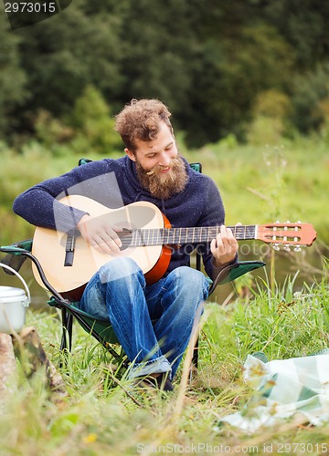 Image of smiling man with guitar and dixie in camping