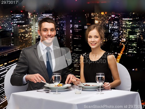 Image of smiling couple eating main course at restaurant