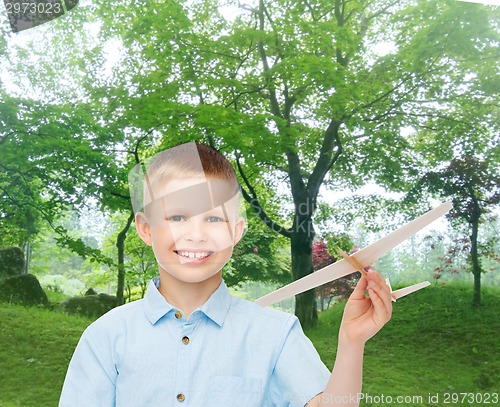 Image of smiling little boy holding a wooden airplane model