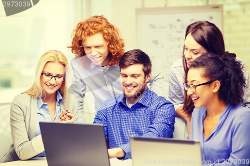 Image of smiling team with laptop computers in office