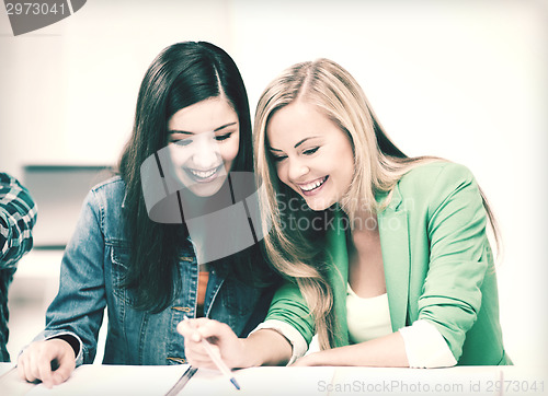 Image of student girls pointing at notebook at school