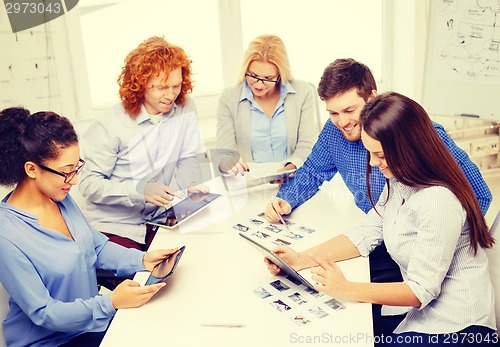 Image of smiling team with table pc and papers working