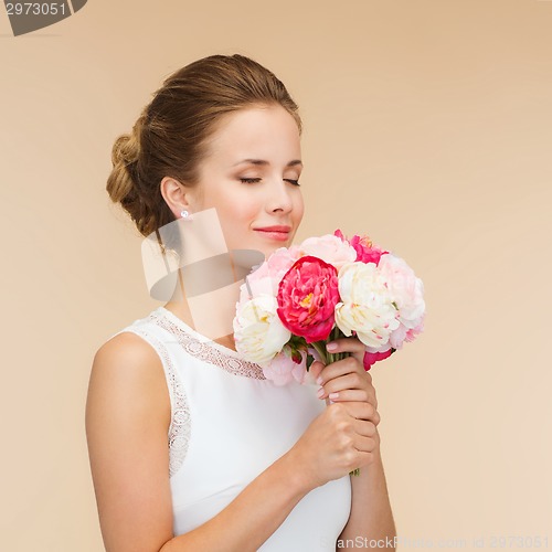 Image of smiling woman in white dress with bouquet of roses