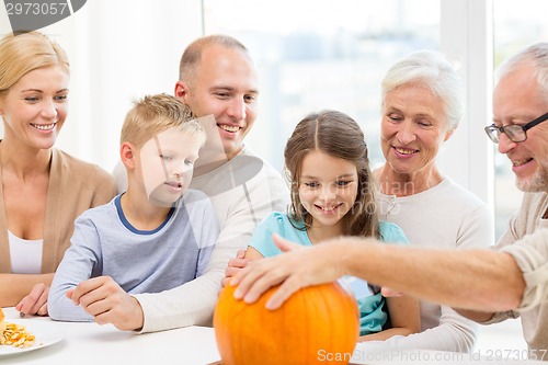 Image of happy family sitting with pumpkins at home