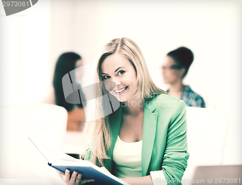 Image of smiling student girl reading book at school