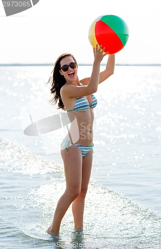 Image of smiling teen girl in sunglasses with ball on beach