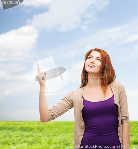 Image of smiling teenage girl pointing finger up