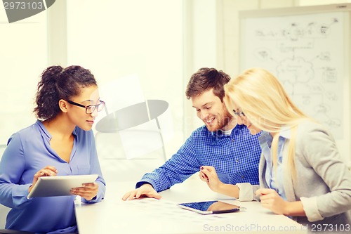 Image of smiling team with table pc and papers working