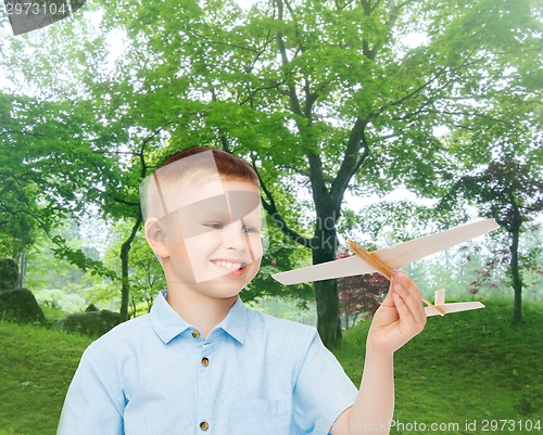 Image of smiling little boy holding a wooden airplane model