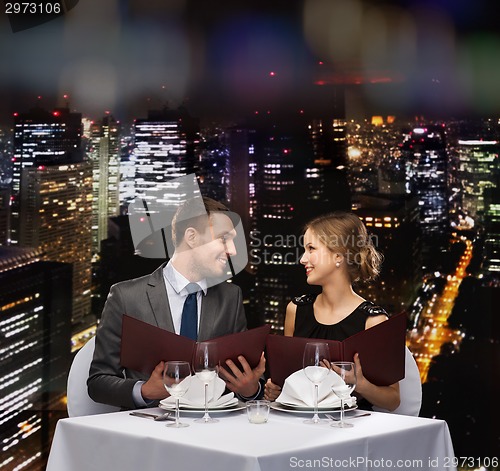 Image of smiling couple with menus at restaurant