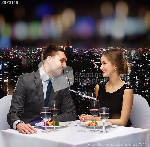 Image of smiling couple eating main course at restaurant