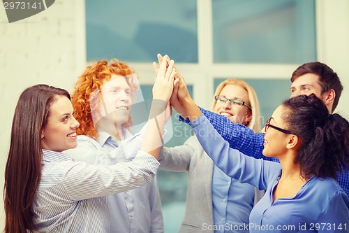 Image of creative team doing high five gesture in office