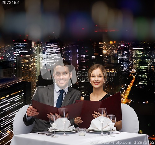 Image of smiling couple with menus at restaurant