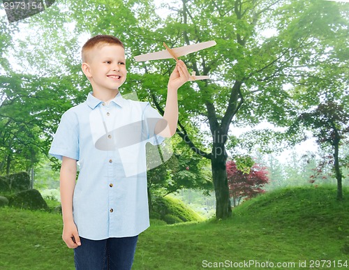 Image of smiling little boy holding a wooden airplane model