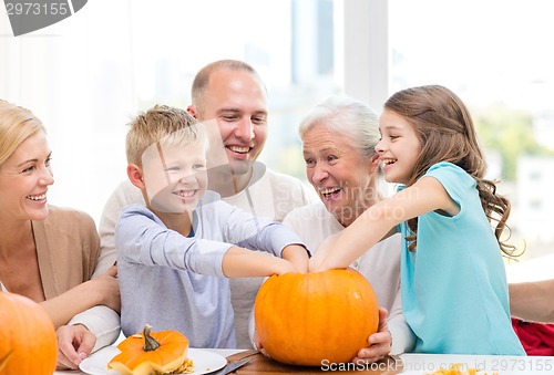 Image of happy family sitting with pumpkins at home