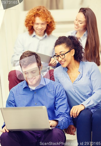 Image of team with laptop and tablet pc on staircase