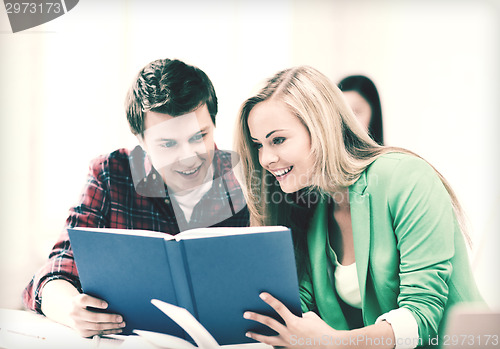 Image of girl and guy reading book at school