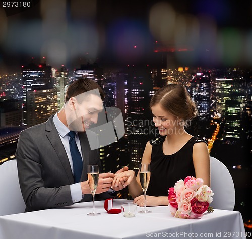 Image of man proposing to his girlfriend at restaurant