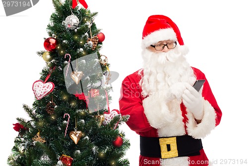 Image of santa claus with smartphone and christmas tree