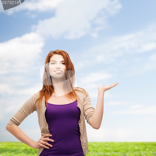 Image of smiling teenage girl holding something on her palm