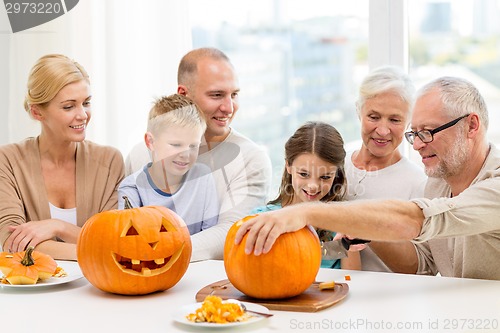 Image of happy family sitting with pumpkins at home