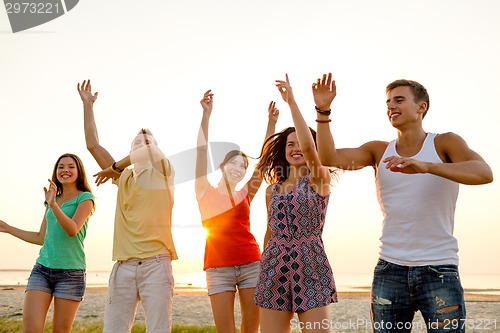 Image of smiling friends dancing on summer beach