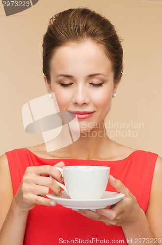 Image of smiling woman in red dress with cup of coffee