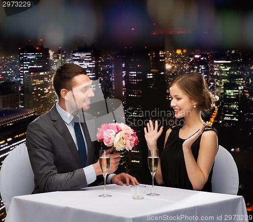 Image of smiling man giving flower bouquet to woman