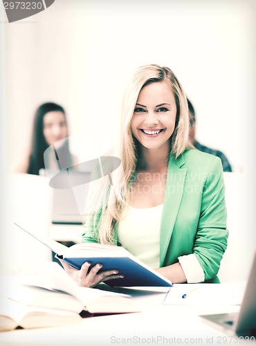 Image of smiling young woman reading book at school